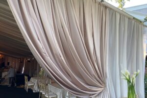 Outdoor wedding decor tent champagne satin perimeter ivory sheer layering drapery event rental