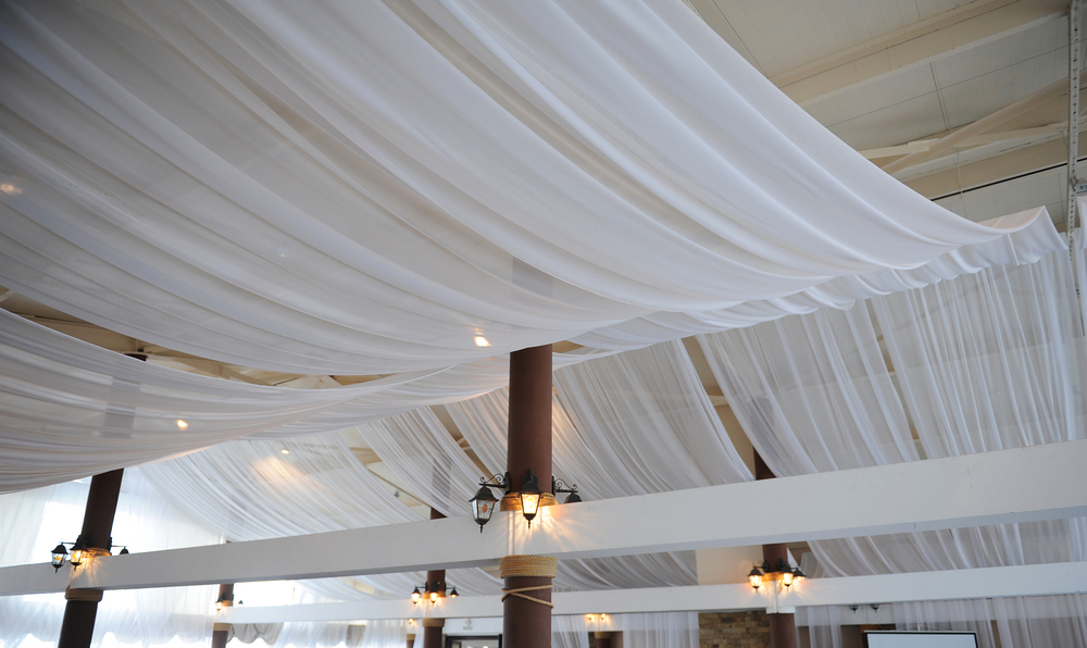 Fabric drape on the ceiling. Bright interior, lighted lantern. Decor for the wedding party
