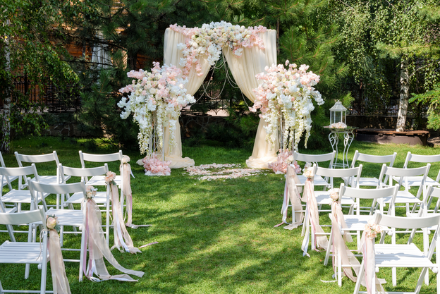 Wedding arch decorated with drape and flowers outdoors